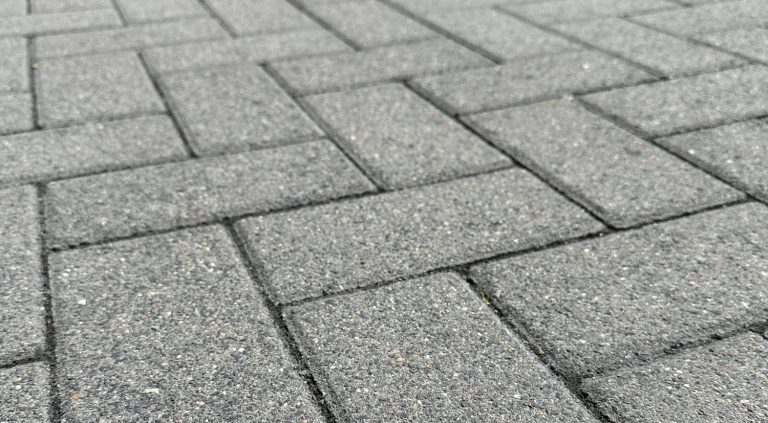 Hochdruckreinigung Grau gepflasterter Boden mit einem geometrischen Muster aus Rechtecken.